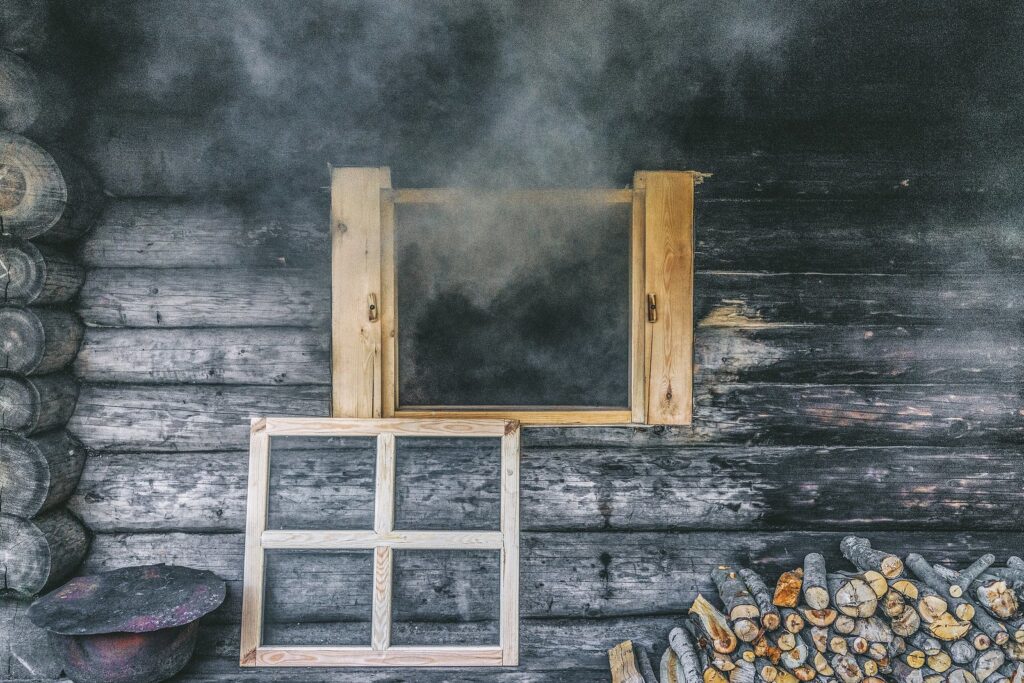 Black smoke flows through the window of a traditional smoke sauna in Estonia. 