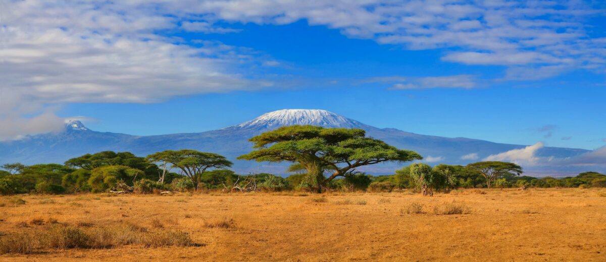 Kilimanjaro mountain Tanzania snow capped under cloudy blue skies captured whist on safari in Africa Kenya.