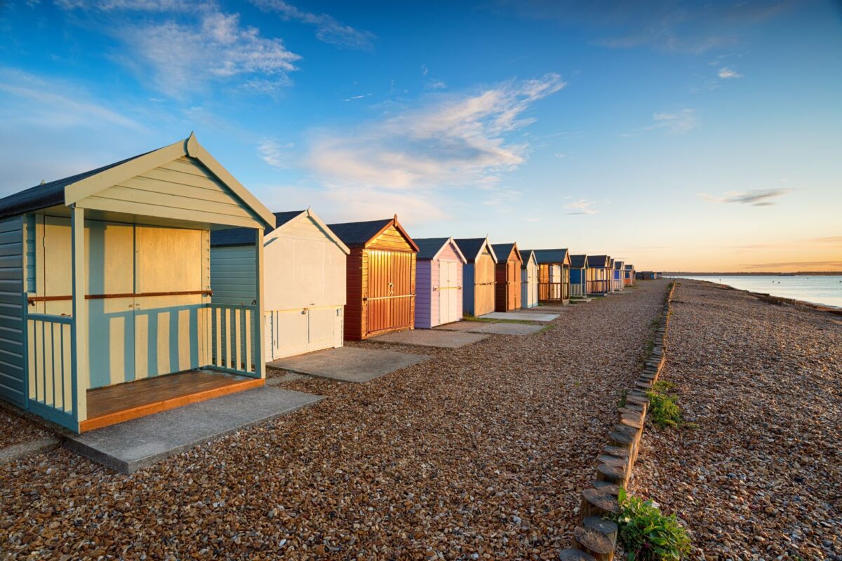 A row of colourful beach huts on the Solent at Calshot on the edge of the New Forest near Southampton in Hampshire.