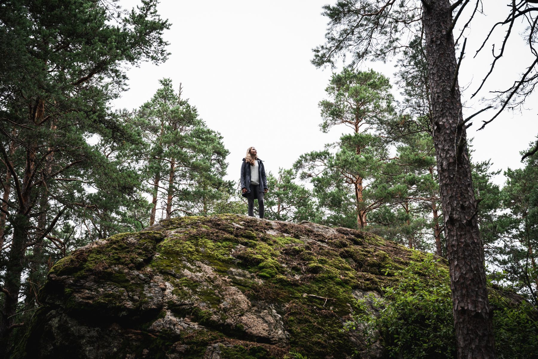 A woman standing on the Majakivi boulder along the trail of the same name in Estonia