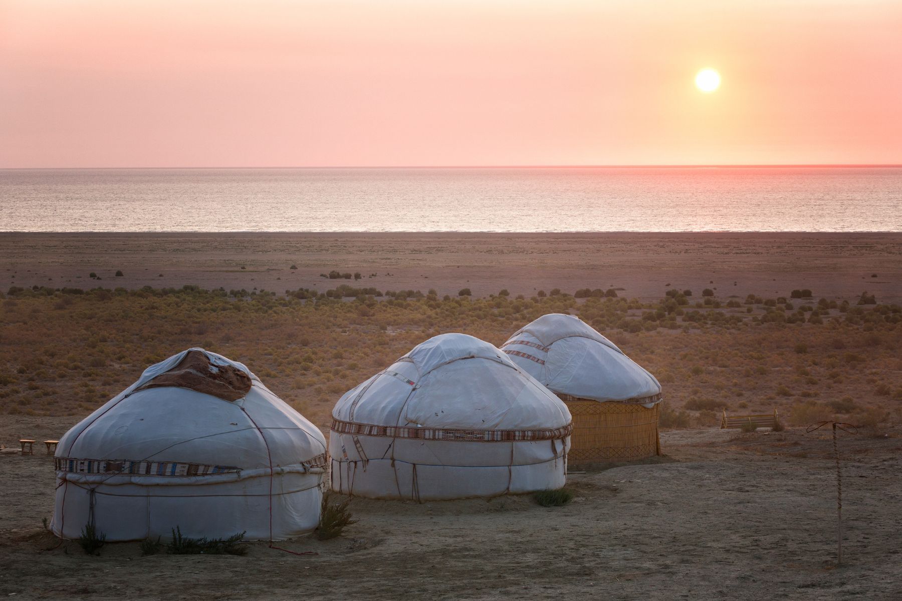 The sun setting on the Aral Sea with three yurts in the foreground, Karakalpakstan