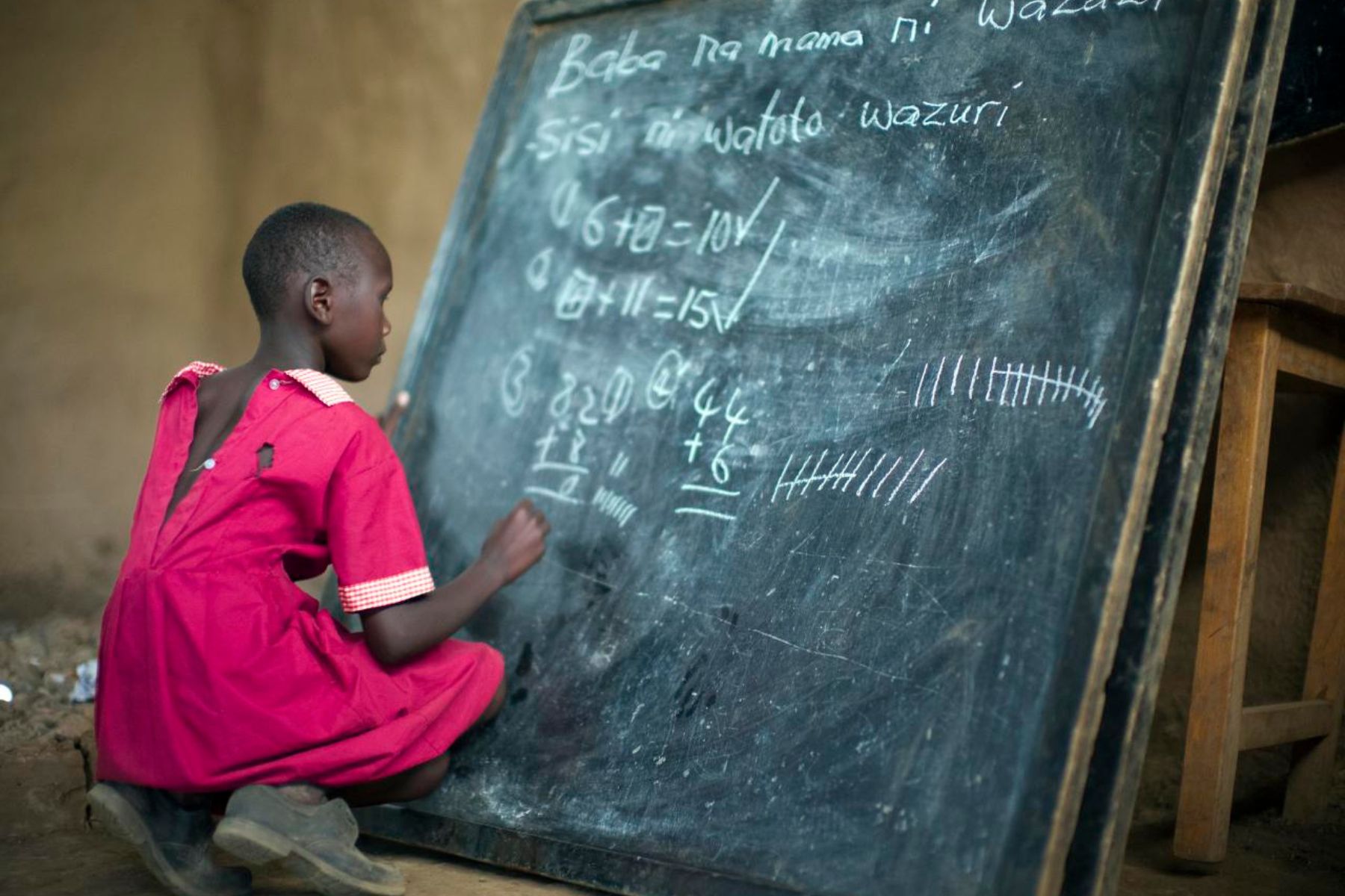 A Masai school girl doing maths on a chalkboard in Swahili, Kenya