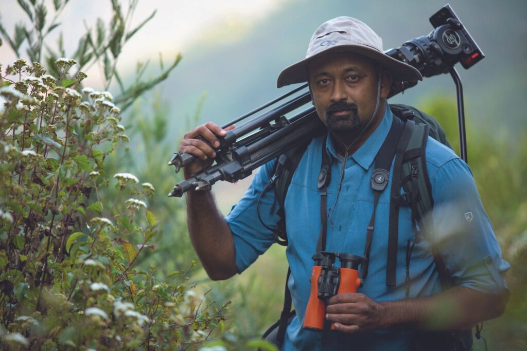 Sandesh Kadur with equipment amongst foliage, Swarovski Optik