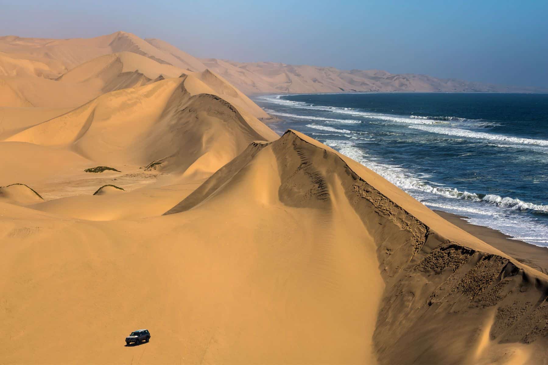 The Namib desert as it borders the sea, a vehicle on a self-drive safari in the foreground