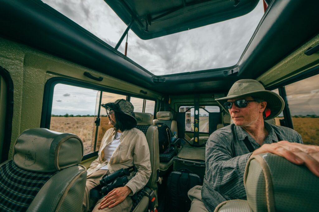 A couple dressed for safari in the back of a vehicle, Tanzania