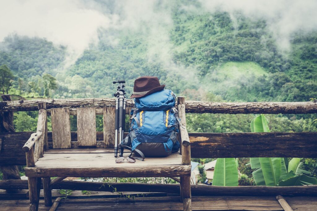 A travel backpack on a wooden bench amongst woods and mountains