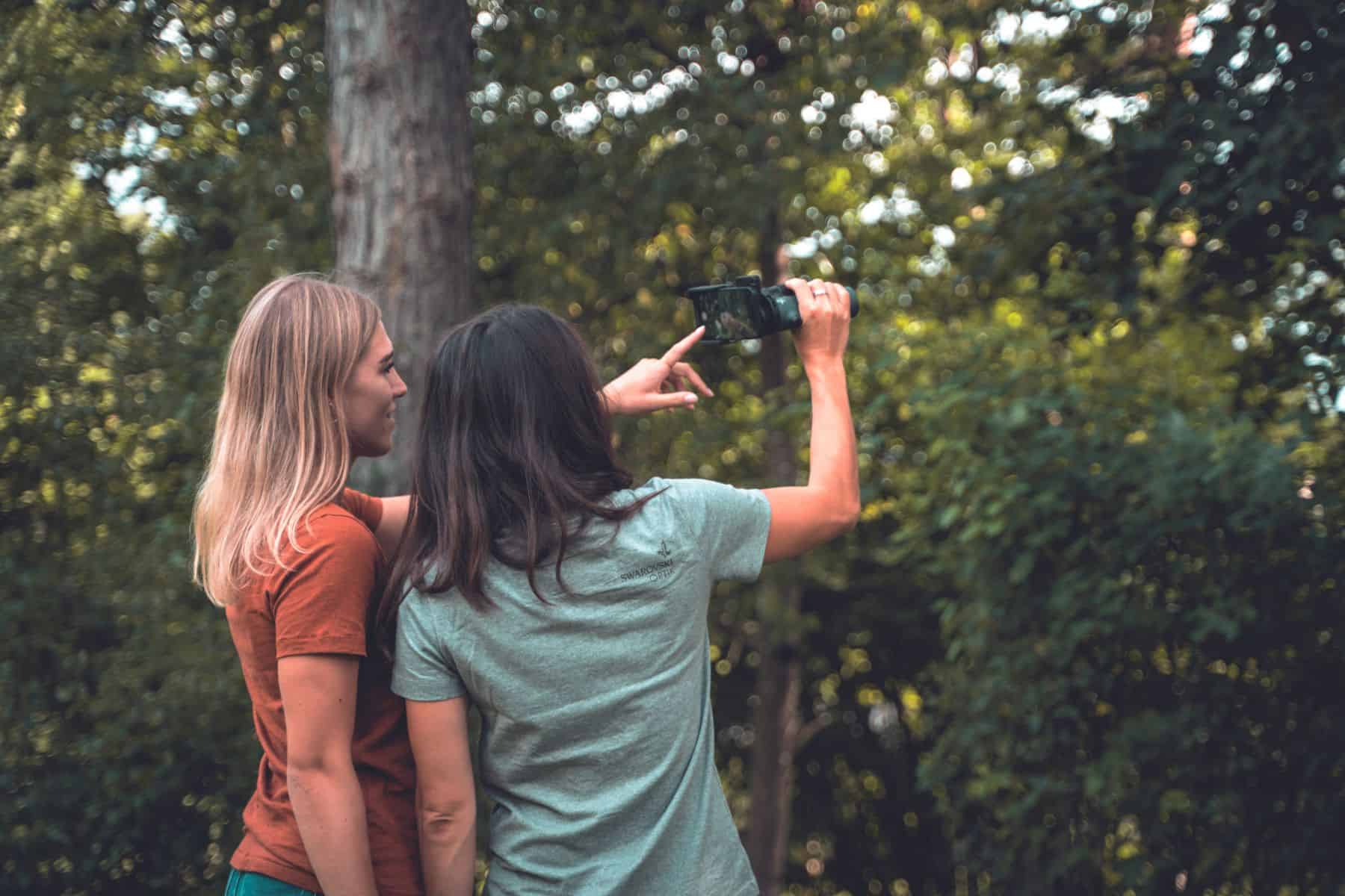 Two women holding up a smartphone with an attached scope