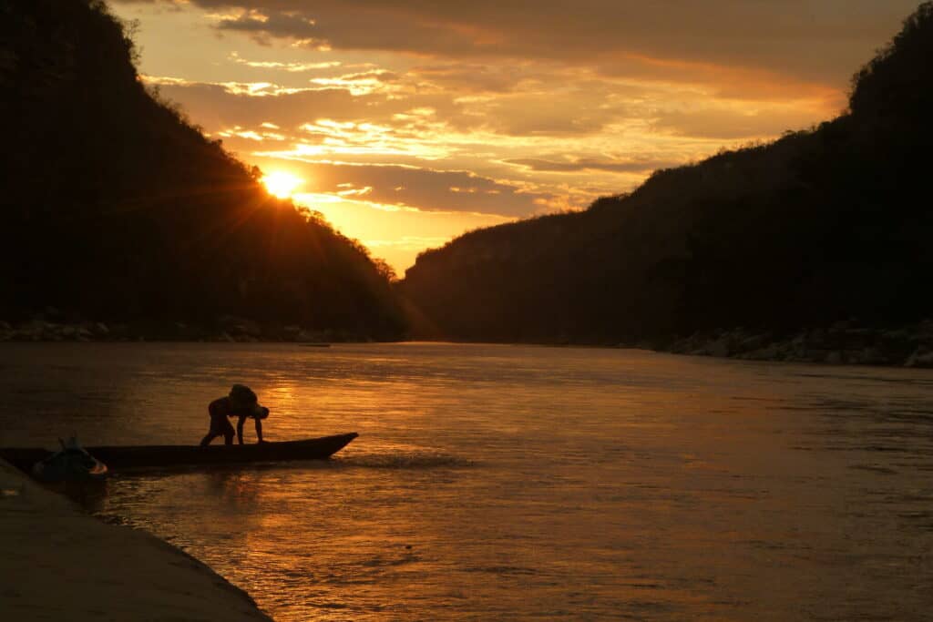 Man pushes his canoe out into the water at sunset in Madagascar 