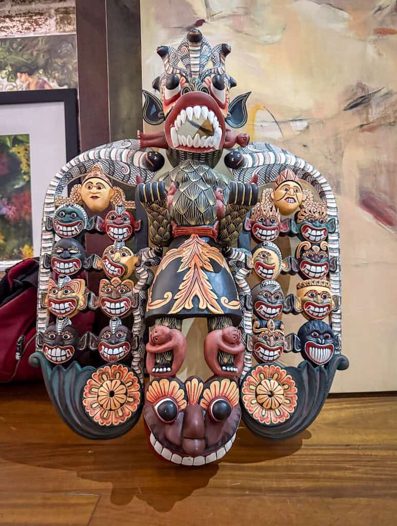 Colourful mask with many heads resting on a wooden table - Sri Lanka's traditional masks 