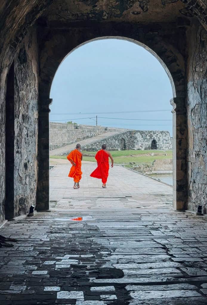Two monks walking through an archway at Jaffna Fort in Sri Lanka - Sri Lanka's traditional masks 