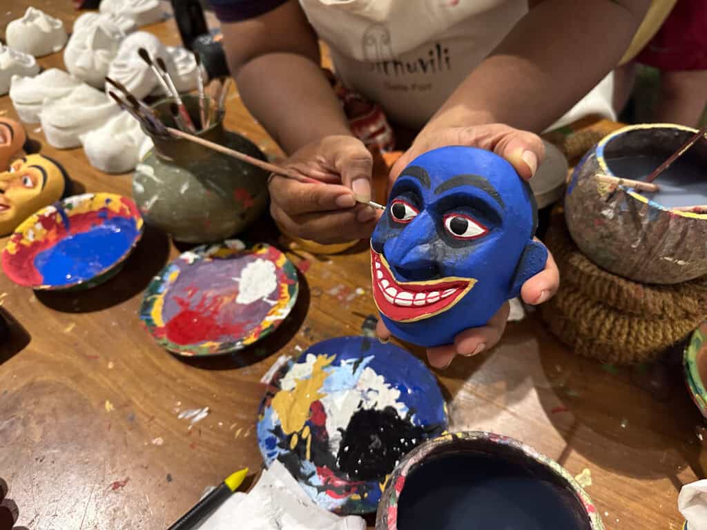 Man painting a mask bright blue at a mask making workshop in Sri Lanka - Sri Lanka's traditional masks 