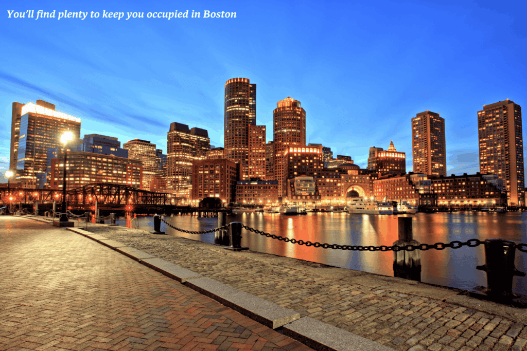 Buildings lit up by the river at night in Boston - best train rides in the USA