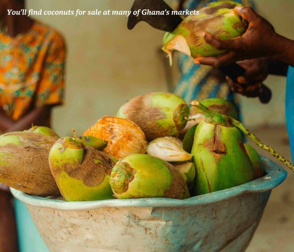 Woman chopping a bowl of coconuts at a market in Ghana