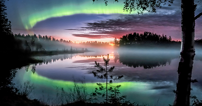 The northern lights reflect on the waters of a lake in Finland 